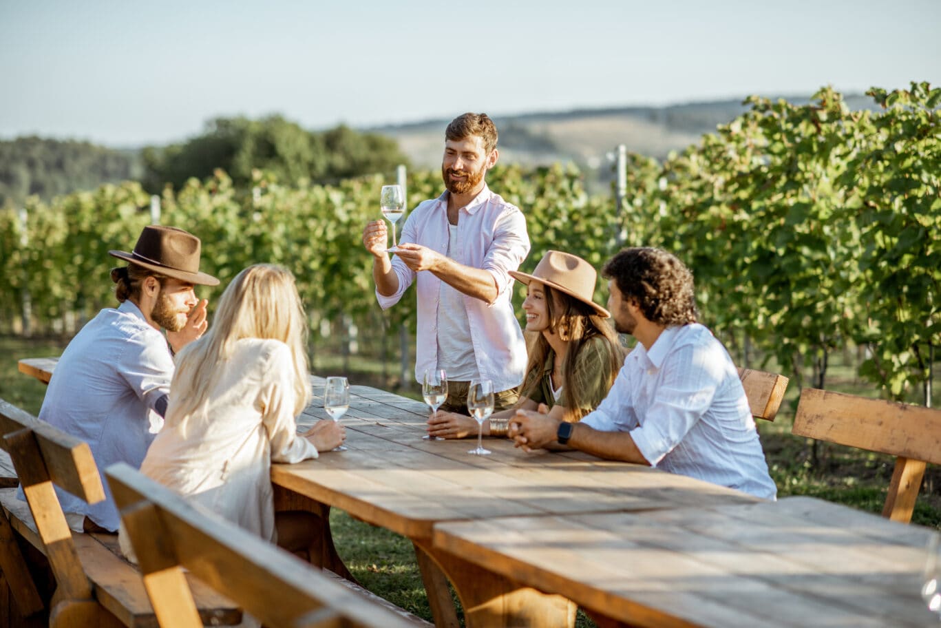 Friends drinking wine at the dining table on the vineyard